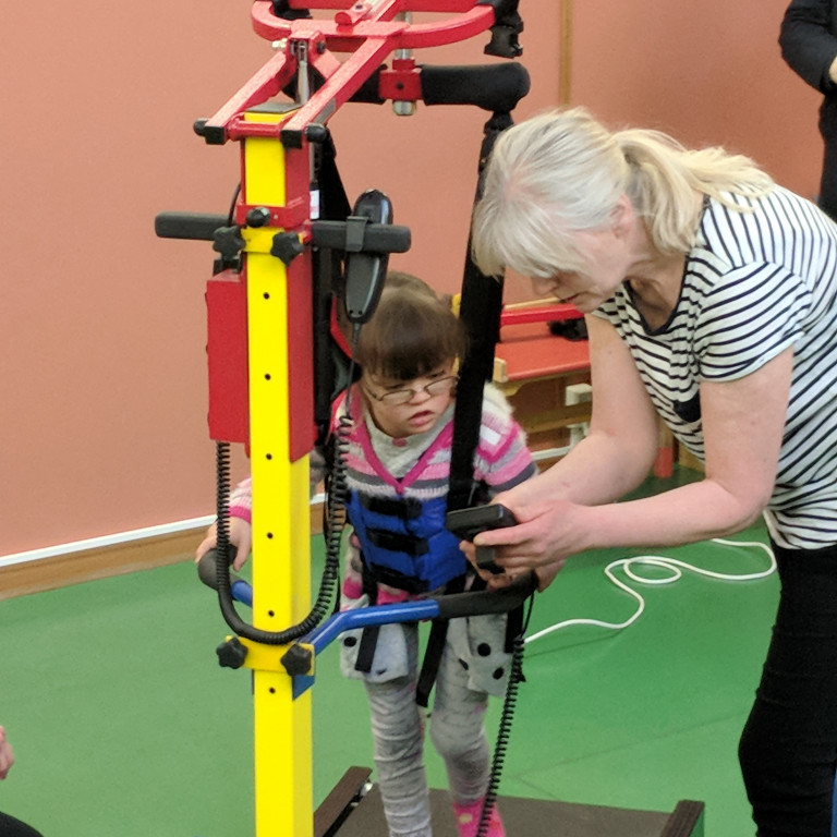 Katrín Sara og Rósa sjúkraþjálfari sýna Trausta og göngubrettið Gönguhrólf í notkun.